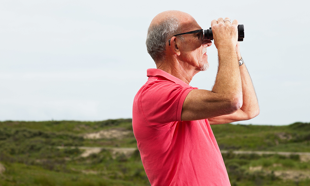 Elder man looking through binoculars