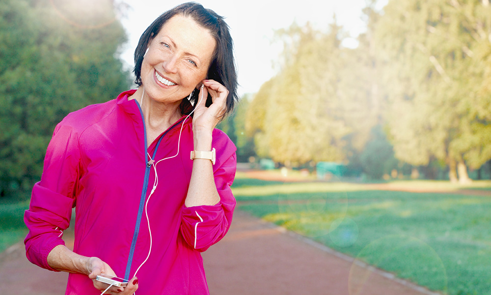 Older woman listening to a podcast on her smartphone during a run