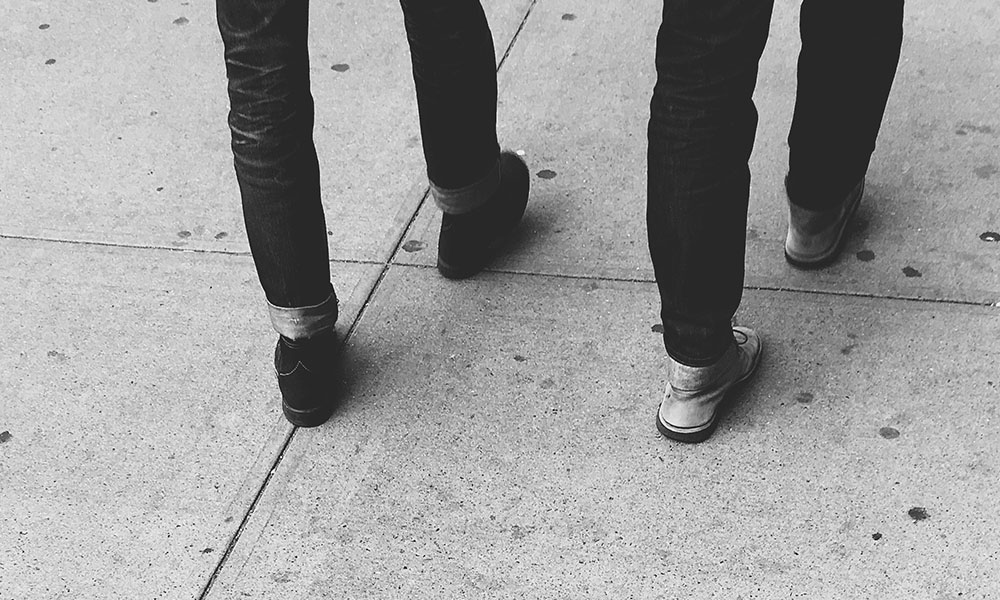 Two people walking on the sidewalk together