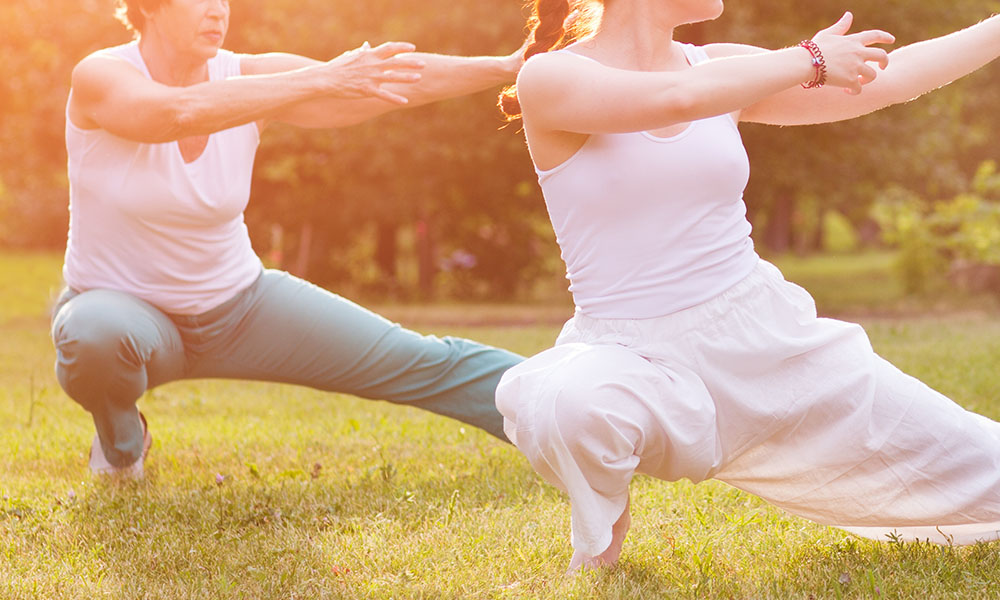 Two women doing tai chi outdoors
