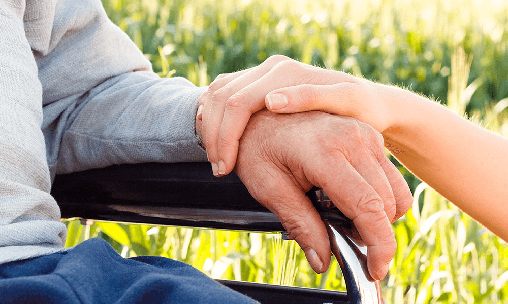 Family caregiver holding on to the hand of the family member being cared for