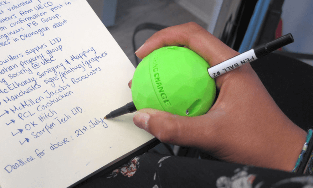  A woman writing with a pen shaped like a ball.