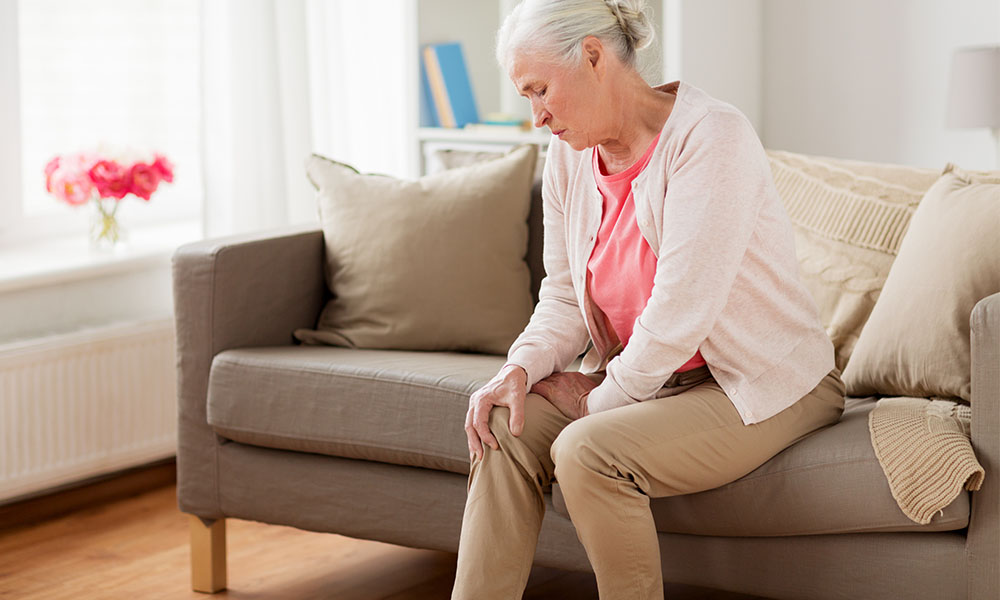  Older Woman Rubbing her Knee While Sitting on the Couch